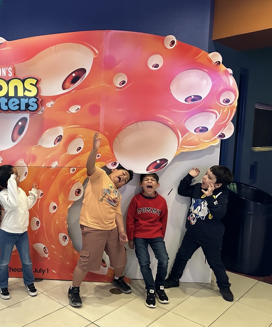Four school-age children posing playfully at a movie theater outing