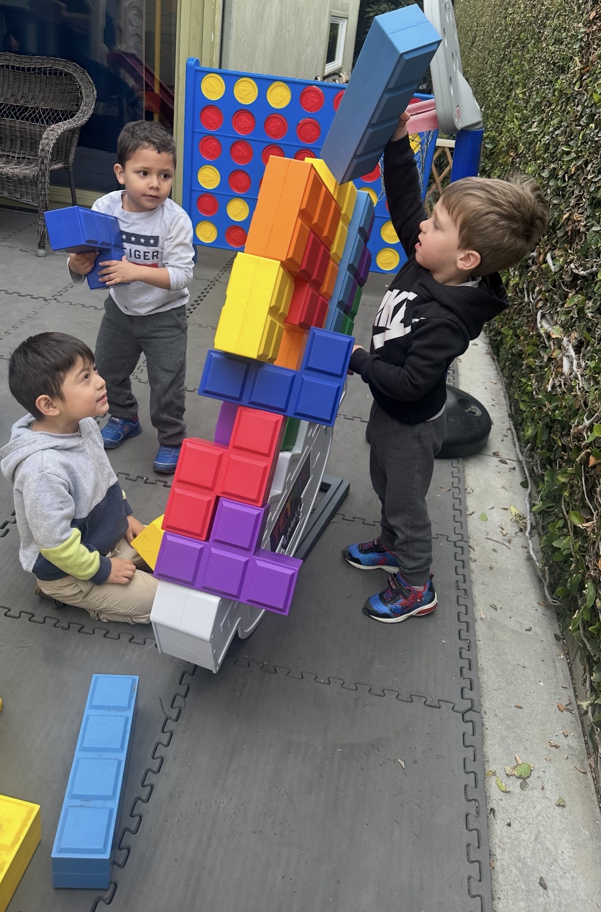 Three children building a tall block tower together