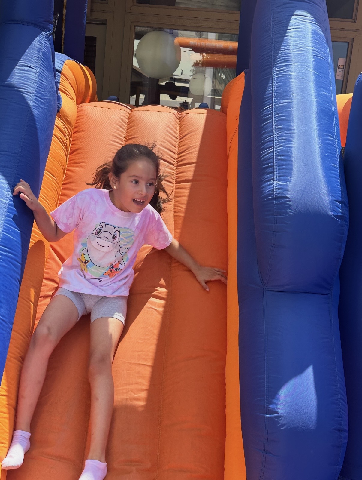 Child sliding down an inflatable bounce house slide