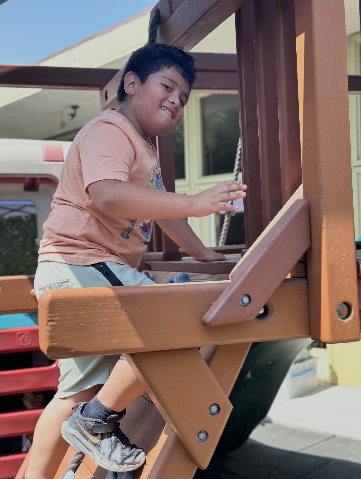 Boy climbing the wooden play structure outside