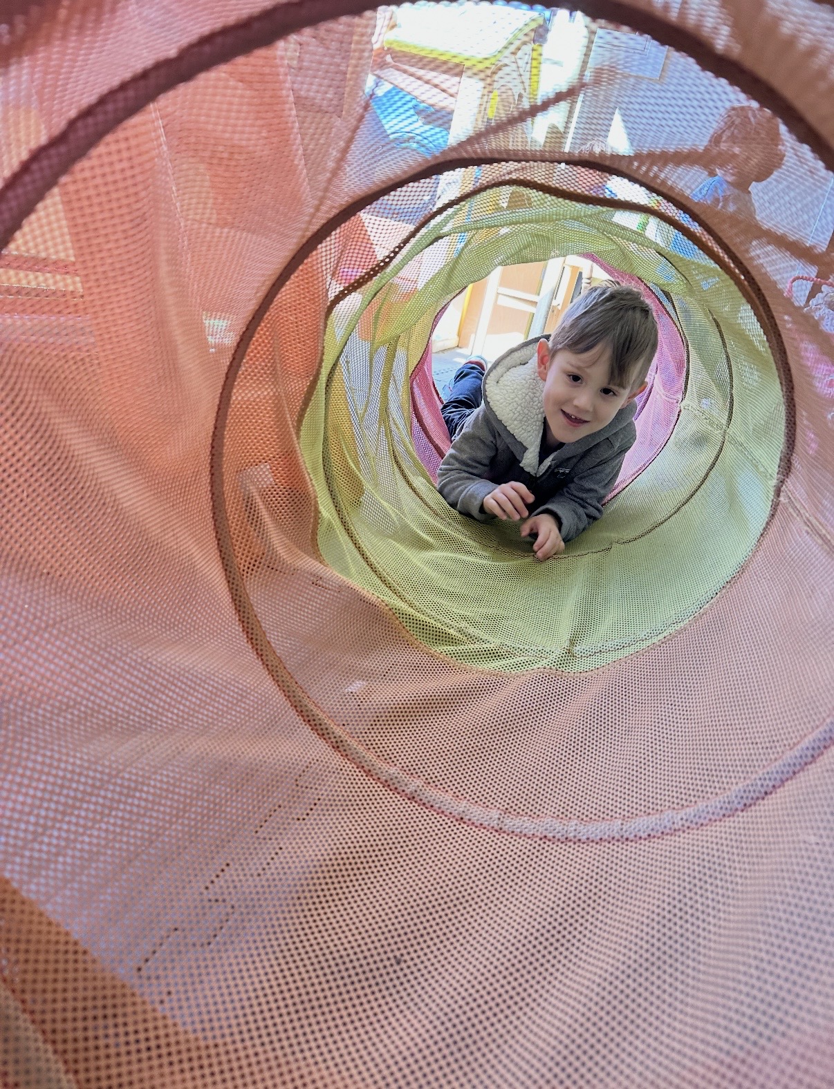 Child crawling through a colorful fabric play tunnel