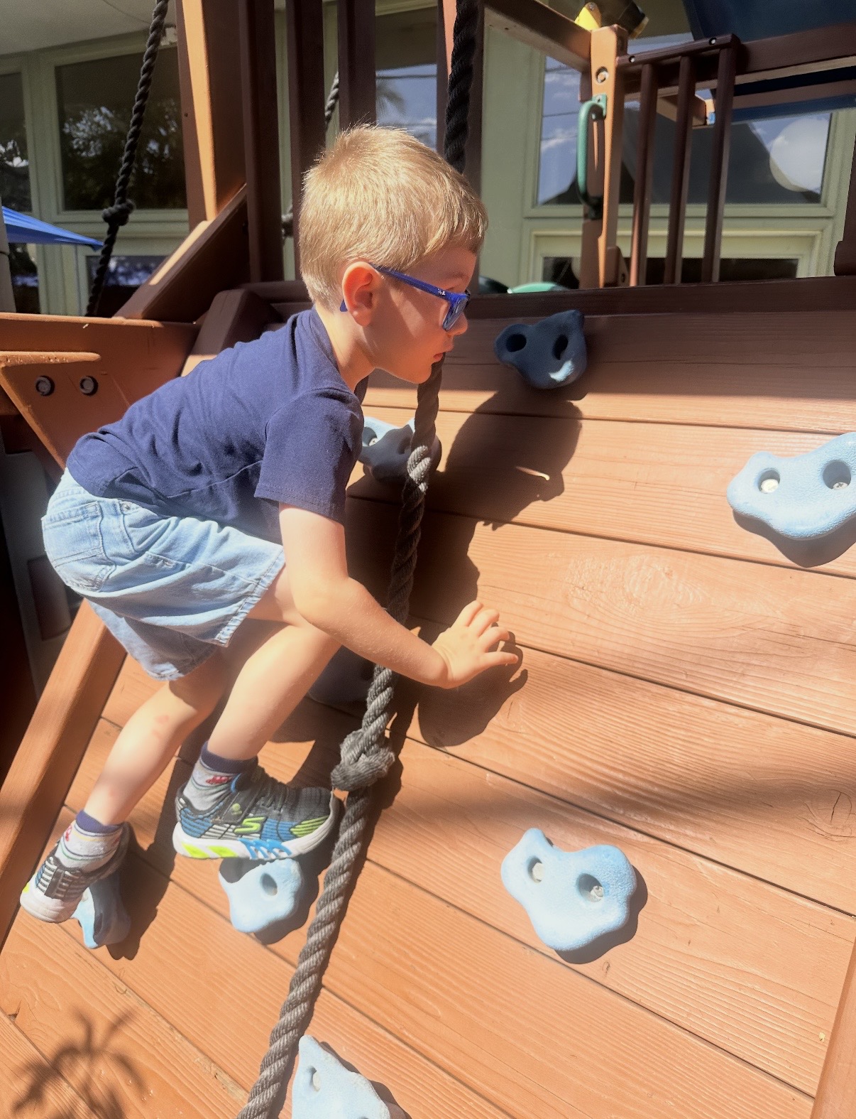 Child climbing the play structure rock wall