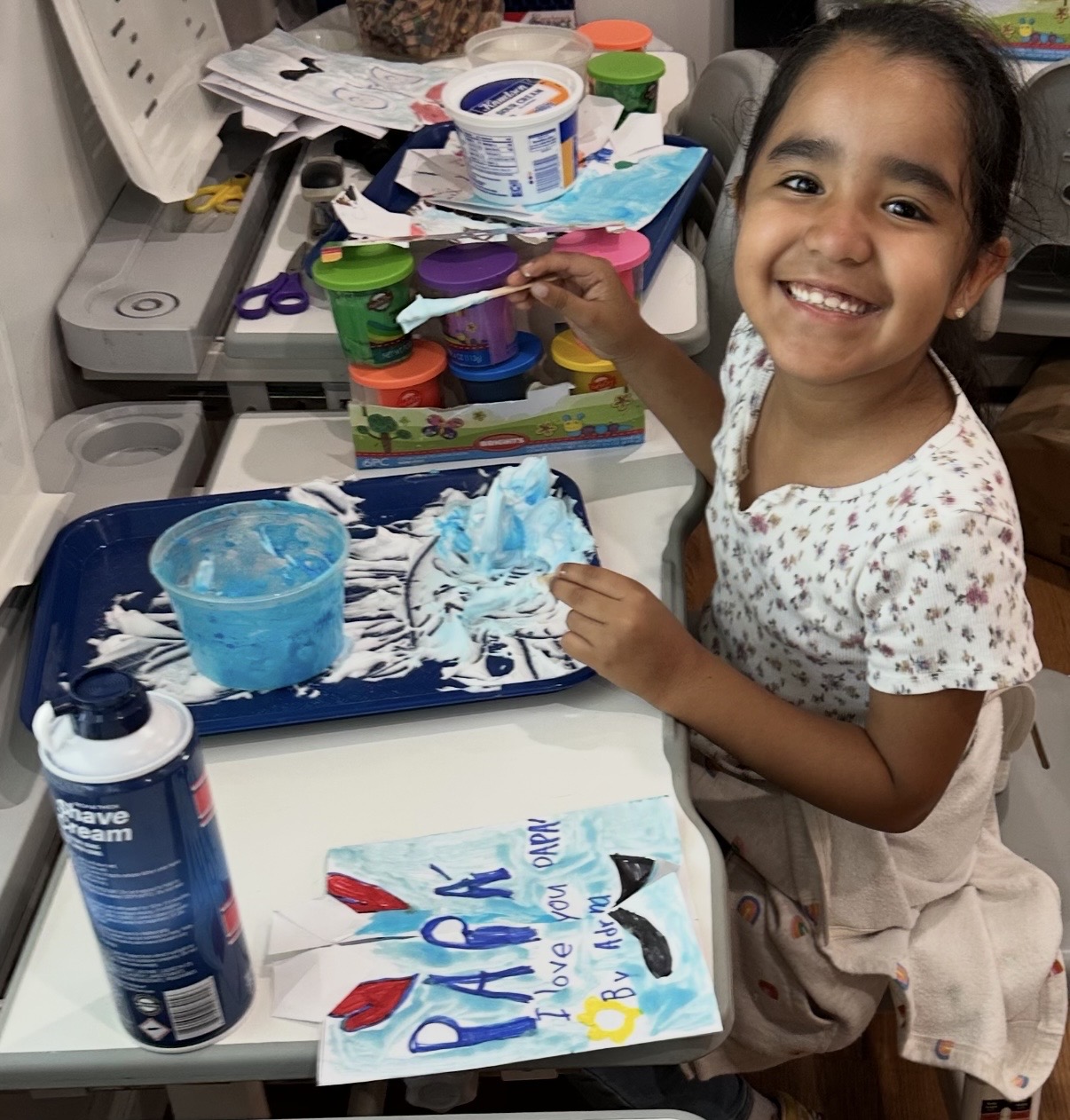 Child smiling beside the Father's Day painting she made
