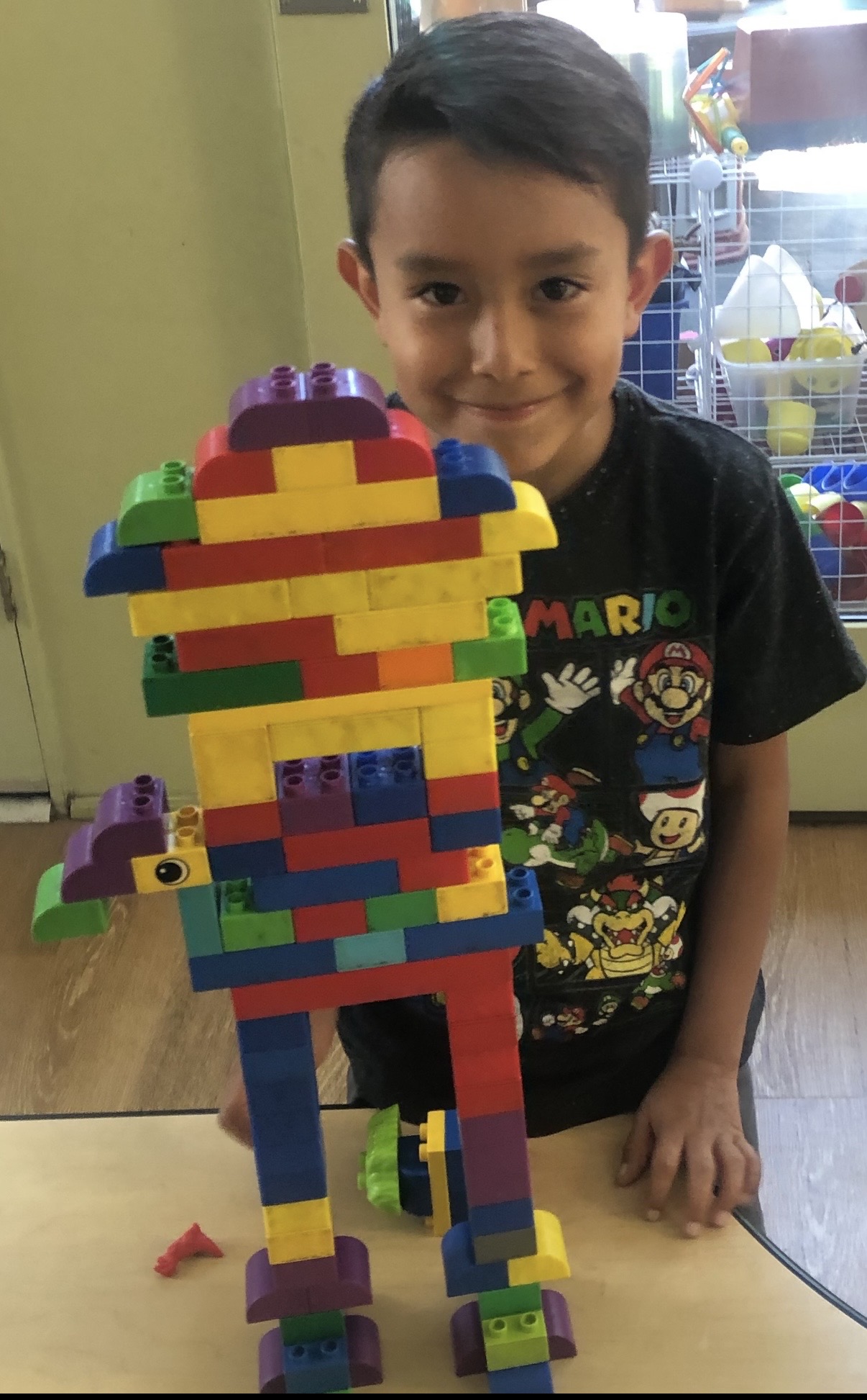 Boy standing proudly next to a tall block figure he built