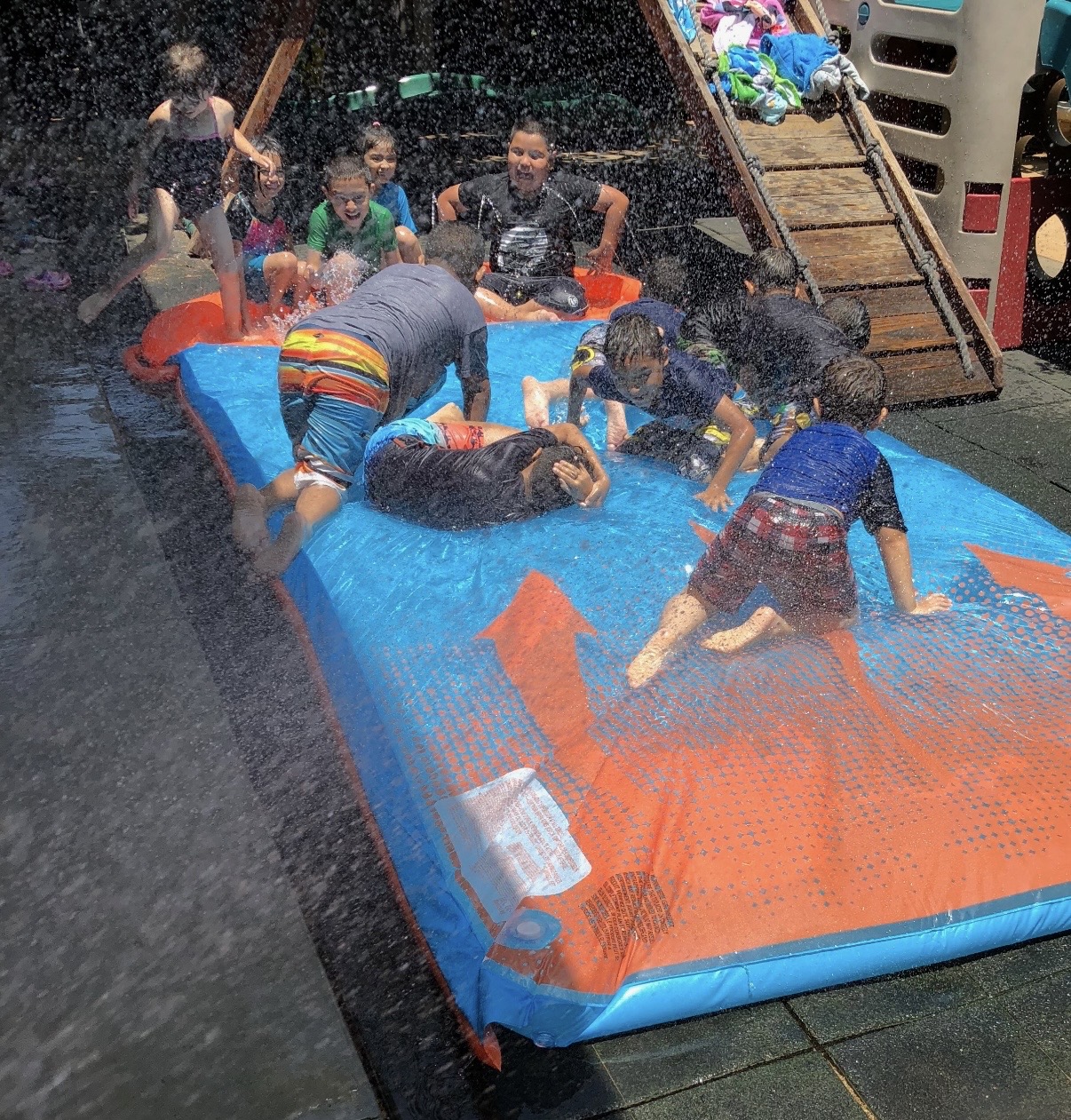 Group of kids sliding and splashing on a big inflatable water slide