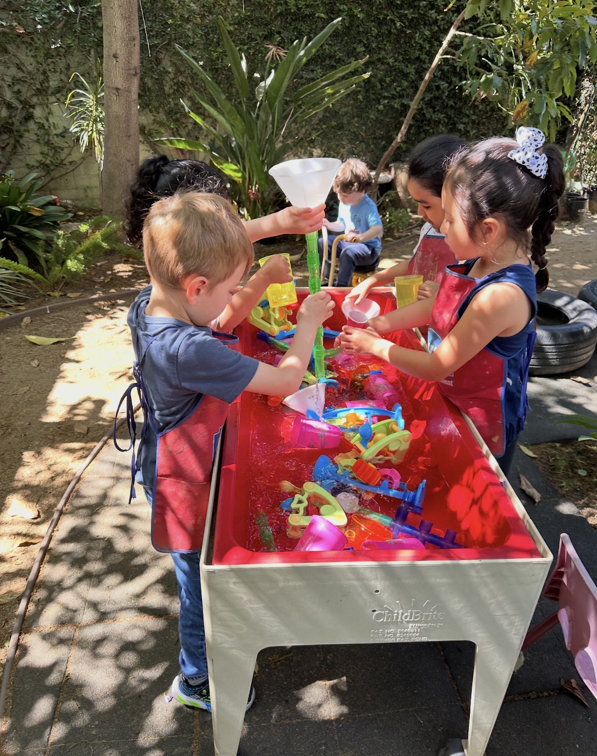 Children pouring and funneling water at the outdoor water table