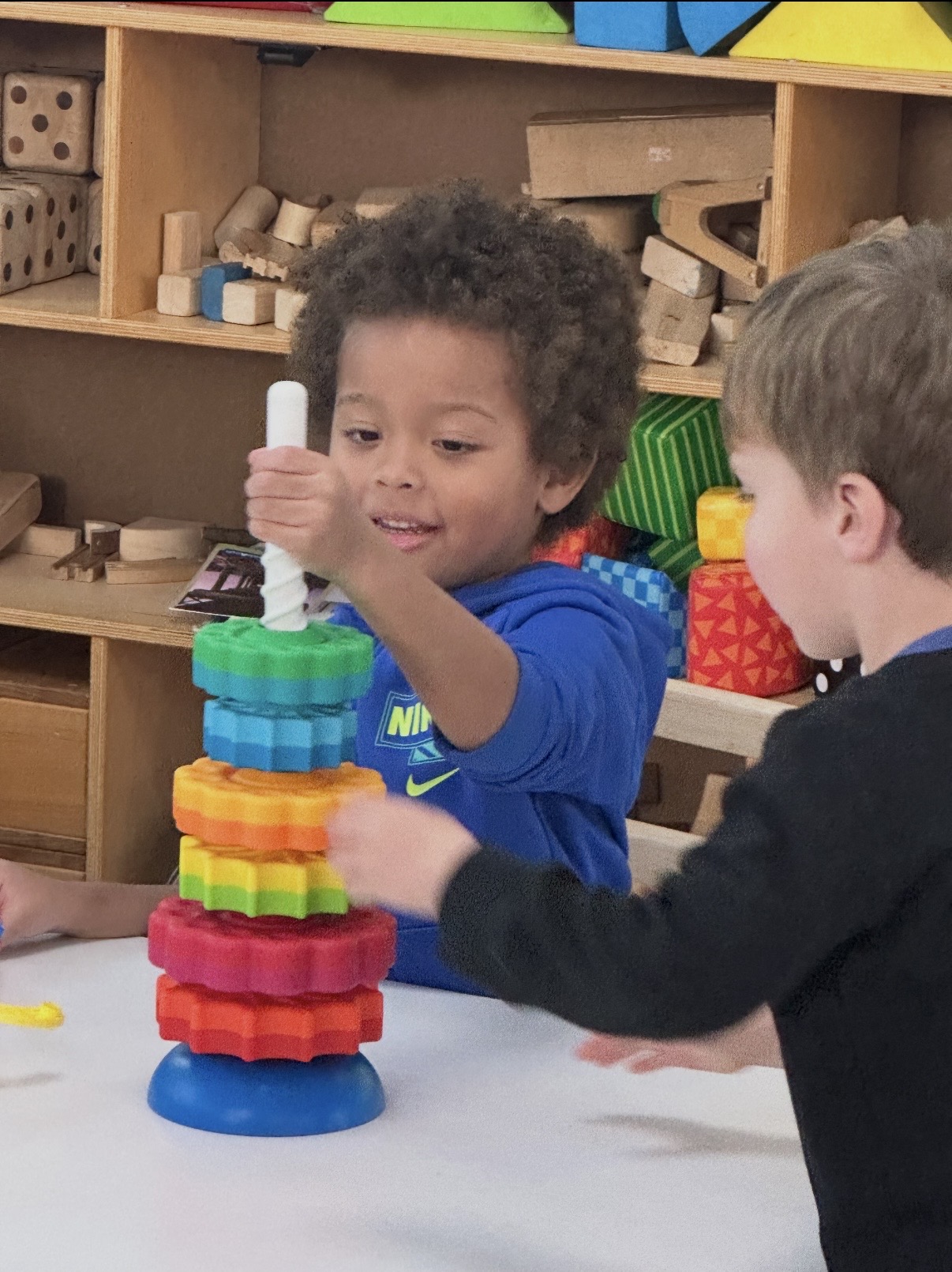Two children stacking a tower of colorful foam rings