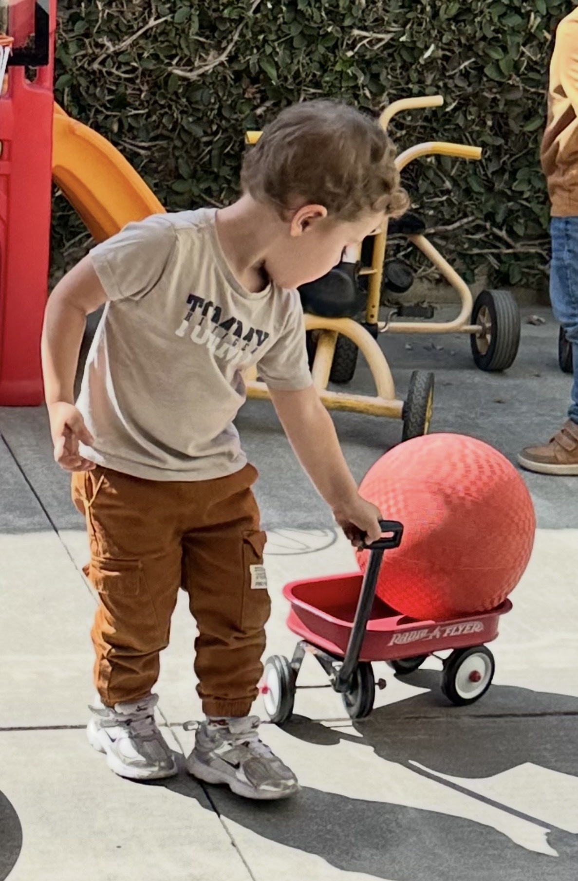 Child pulling a wagon across the play yard at Happy Preschool and Daycare
