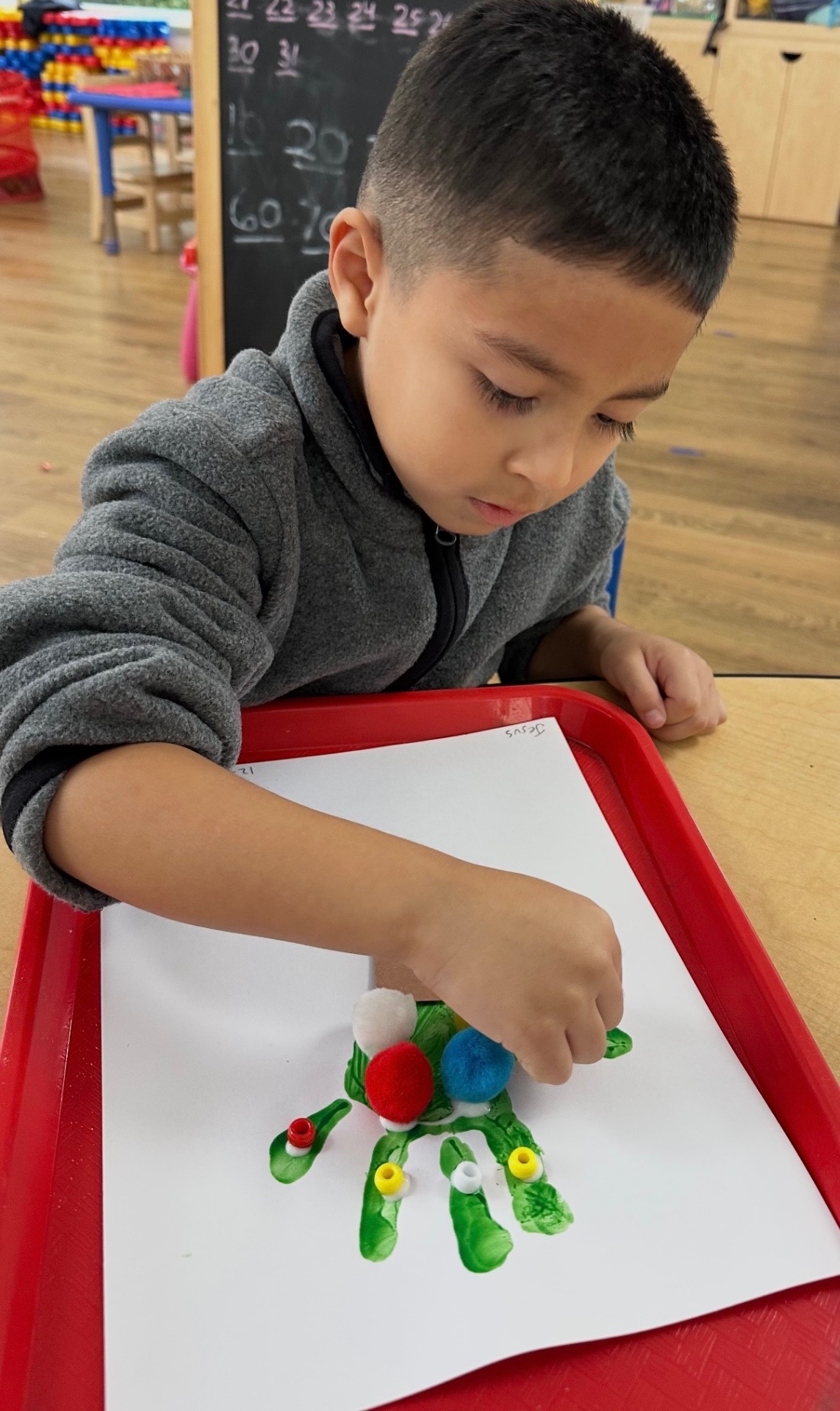 Child making a handprint painting with pom-poms