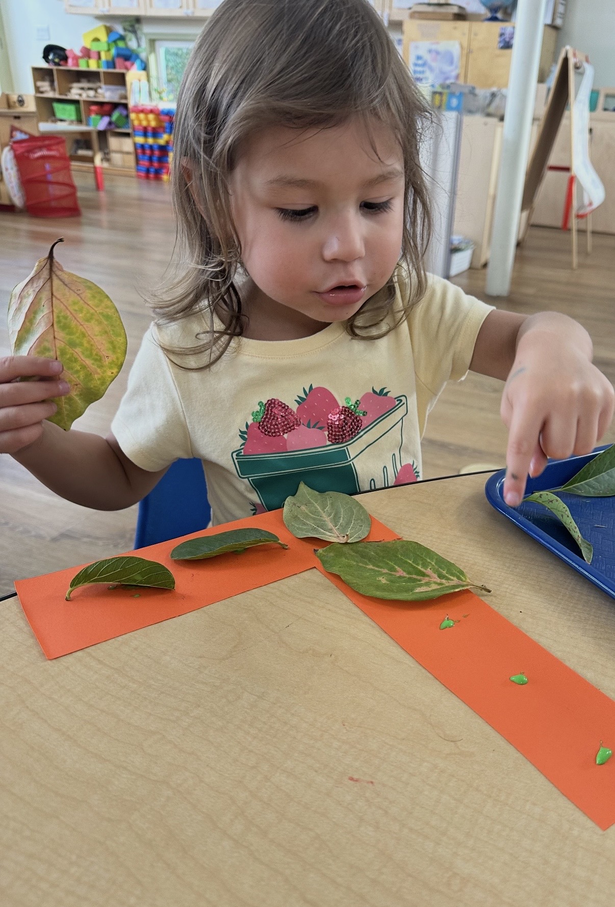 Child arranging leaves on paper for a nature craft