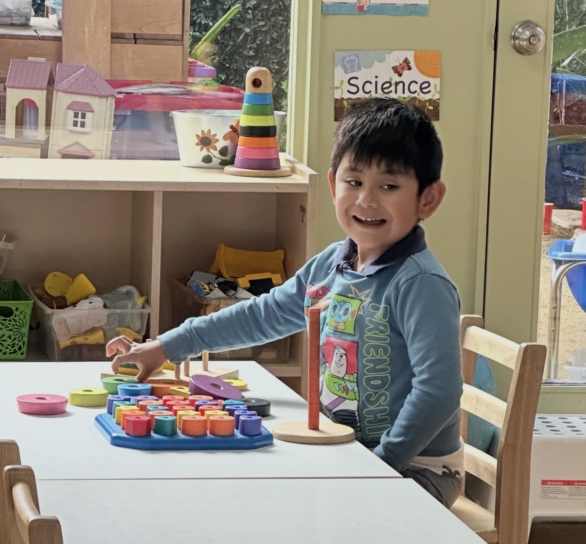 Child stacking colorful wooden rings on a peg board